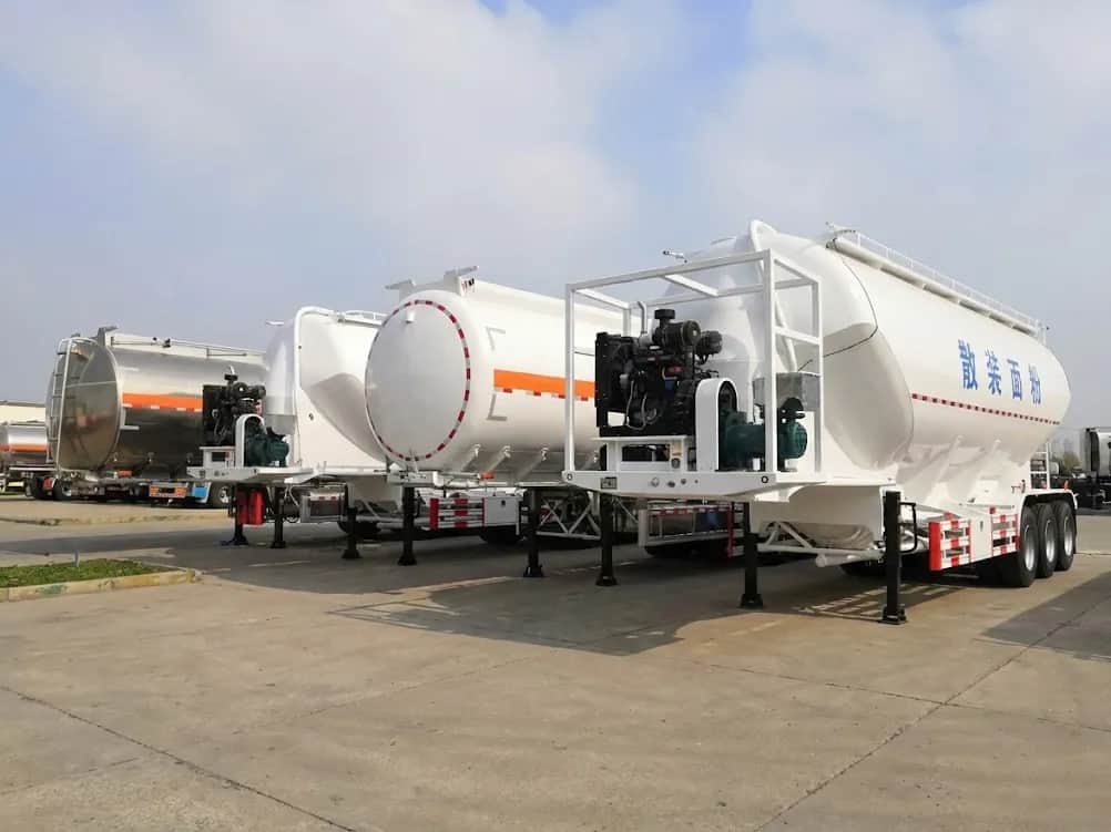Lineup of Kales Vehicle liquid and powder transport trailers featuring aluminum fuel tankers and pneumatic bulk flour tankers with diesel engines.