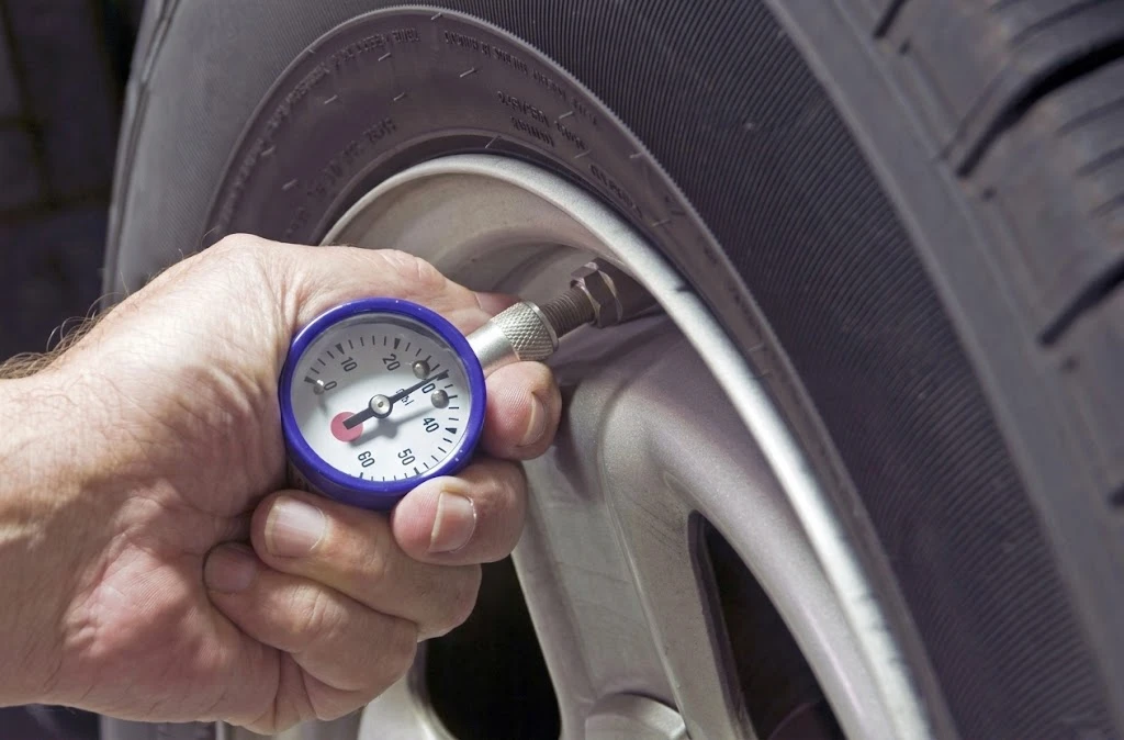 Slash Fuel Costs: How to Save $5,000+ per Truck Annually on Fuel Efficiency 4 A person uses a professional pressure gauge to check a Kales Vehicle truck tire to prevent fuel economy penalties.