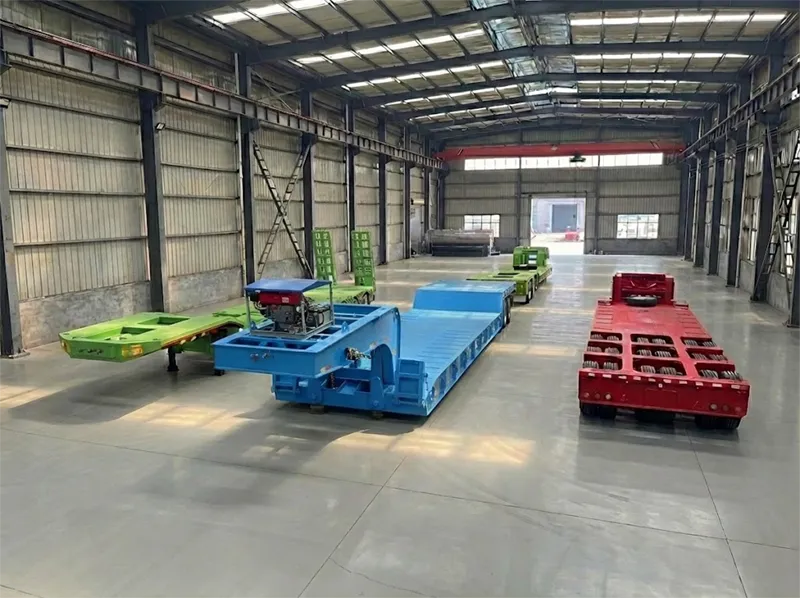 A display of specialized heavy-duty lowbed and detachable gooseneck (RGN) semi-trailers designed for safe machinery and equipment transport, showcased on the Kales Vehicle factory floor.